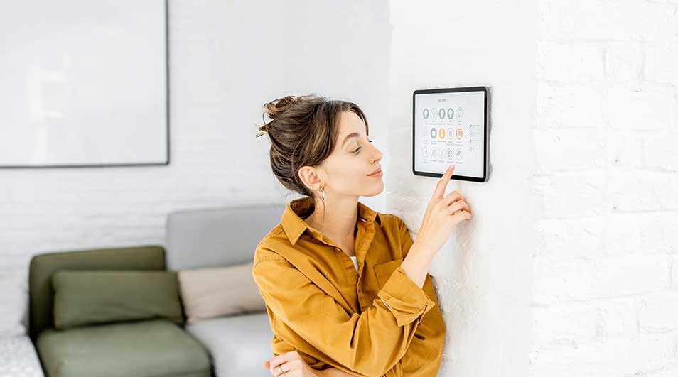 Een tablet hangt aan een witte bakstenen muur met een display. Er staat een groene bank in de kamer.