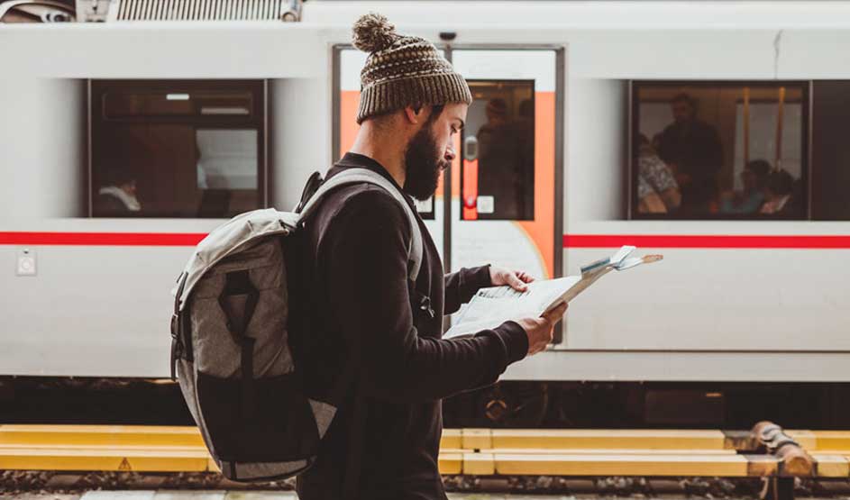 Een trein op een station met een persoon met een rugzak die een kaart leest.