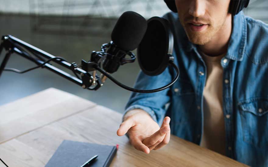 Un microphone noir sur une table en bois avec un carnet gris et un stylo noir.