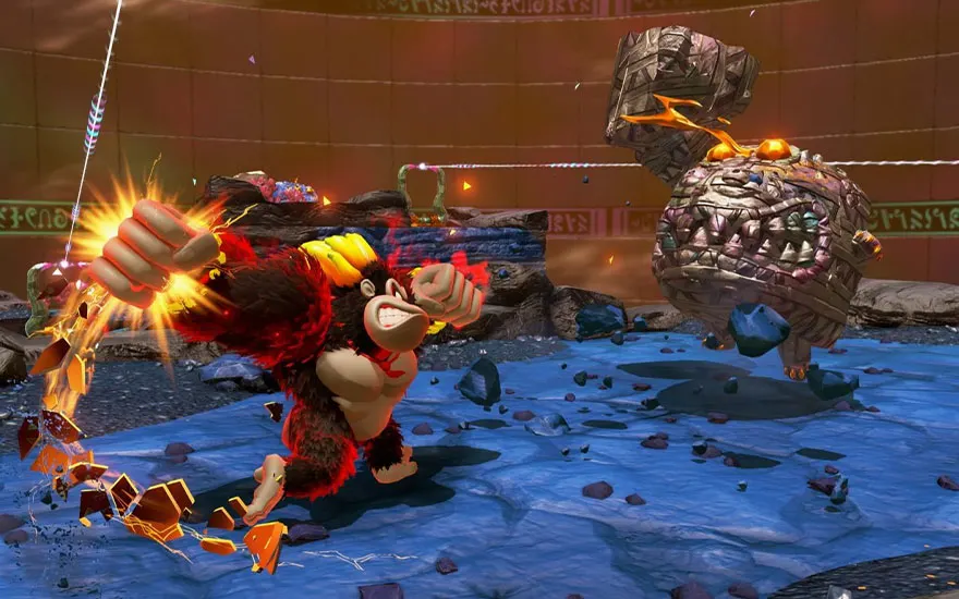 Ik zie Donkey Kong in actie, met een vuist die energie uitstraalt. Hij staat klaar om een zwevende vijand aan te vallen in een arena met water. De omgeving heeft een oud-Egyptisch thema. Het ziet eruit als een gevecht uit een videogame.