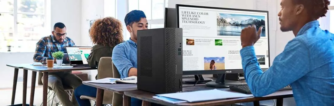 Quatre collègues travaillent ensemble dans un bureau lumineux équipé d’ordinateurs, d’un grand écran et d’un ordinateur fixe.