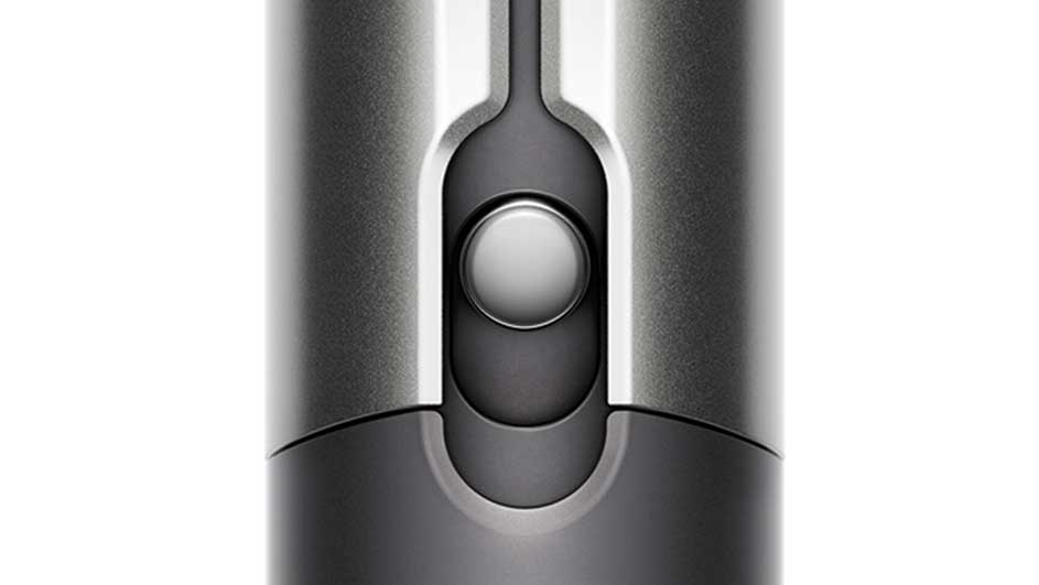 Gros plan d'un bouton rond argenté sur un appareil gris foncé, encadré par des bandes verticales argentées.