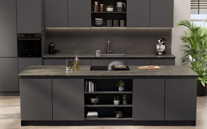 Grijze keuken met eiland. Kasten, een oven, aanrecht met kraan en kookplaat zijn zichtbaar. Decoratie en planten staan op het eiland en de planken.