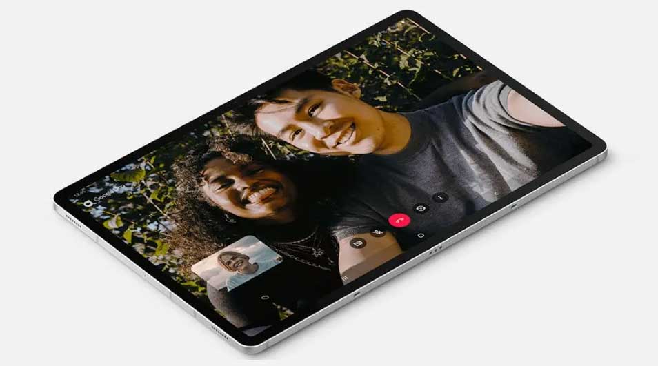 Un écran de tablette affiche un appel vidéo avec deux personnes souriantes, sur fond de verdure.