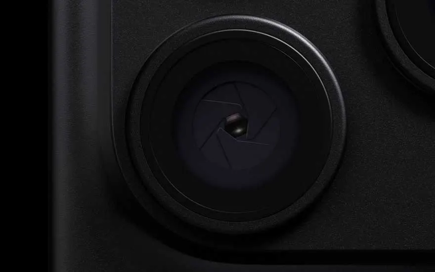 Een extreme close-up toont een grote zwarte cameralens met gesloten diafragmabladen op de donkere behuizing van een fototoestel.