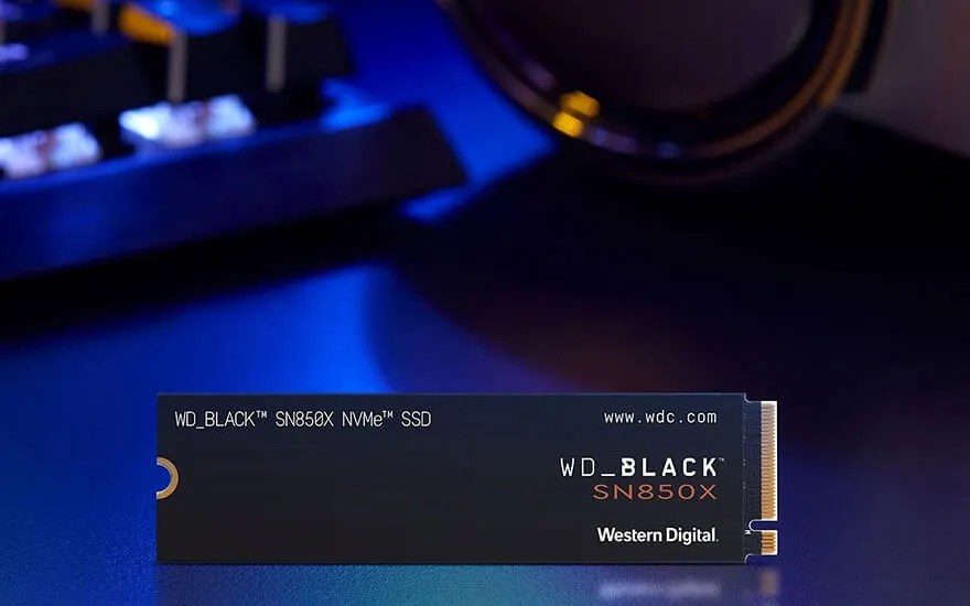 Een WD_BLACK SN850X NVMe SSD ligt op een tafel, omlijst door een toetsenbord en een headset in een sfeervolle blauwe gloed.