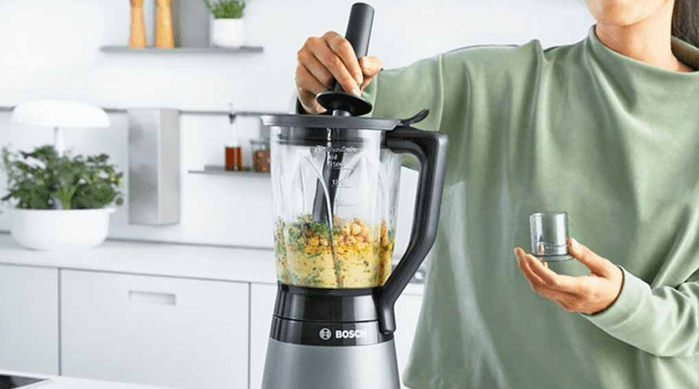 Een Bosch blender op een wit aanrecht met ingrediënten erin, klaar voor gebruik in een moderne keuken.