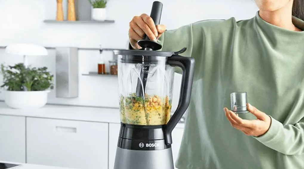 Een Bosch blender op een wit aanrecht met ingrediënten erin, klaar voor gebruik in een moderne keuken.