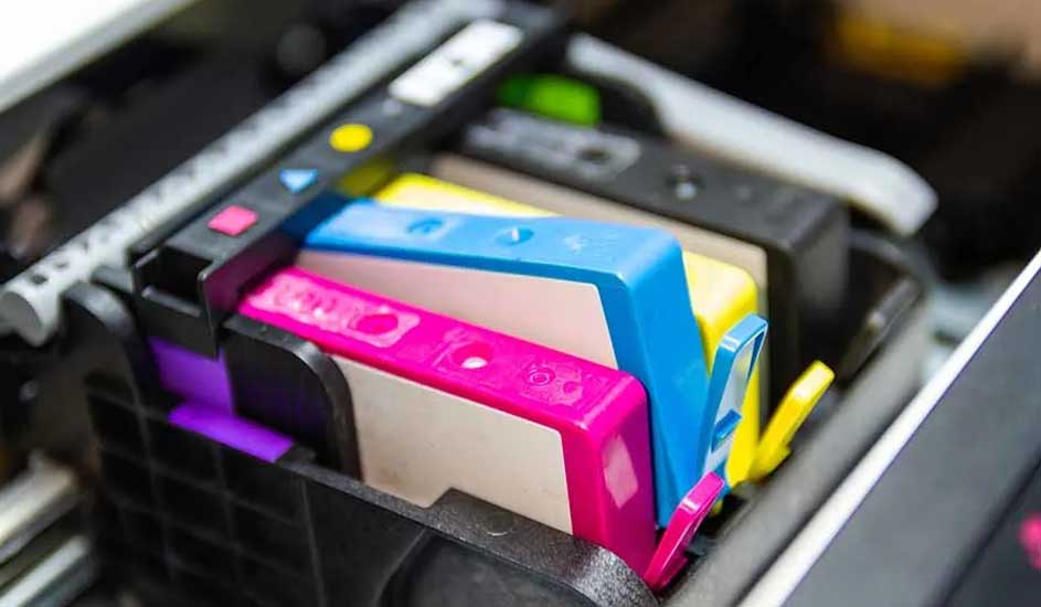 Cartouches d'imprimante colorées (magenta, cyan, jaune) dans un support noir. Autres cartouches visibles à l'arrière.