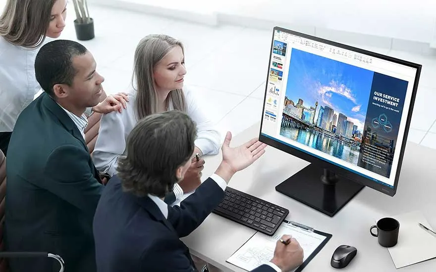 Een computerscherm toont een presentatie met een stadsgezicht. Een toetsenbord, muis, en een notitieblok liggen op het bureau.