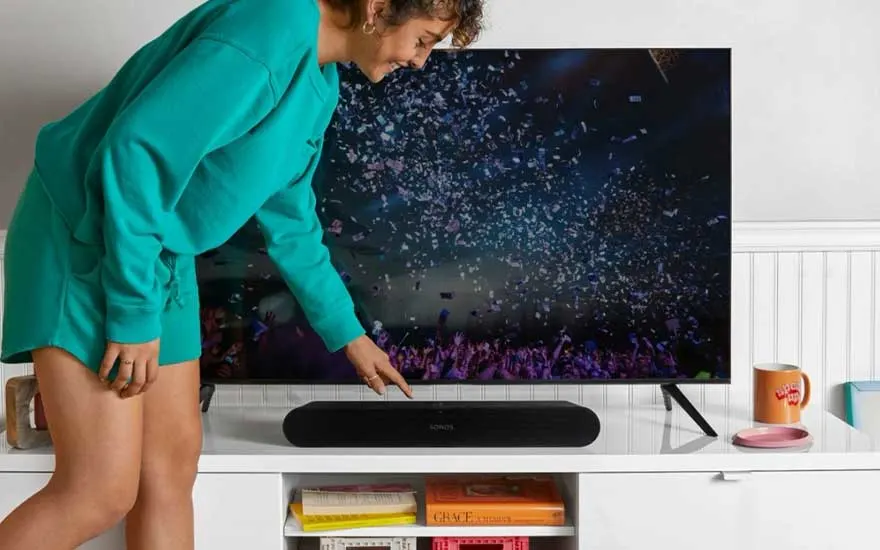 Witte kast met een zwarte soundbar onder een tv. Op de tv is een menigte met confetti te zien.