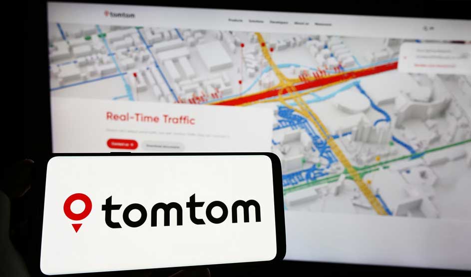 Écran de smartphone affichant le logo TomTom en rouge et noir, avec une carte de navigation détaillée en arrière-plan.
