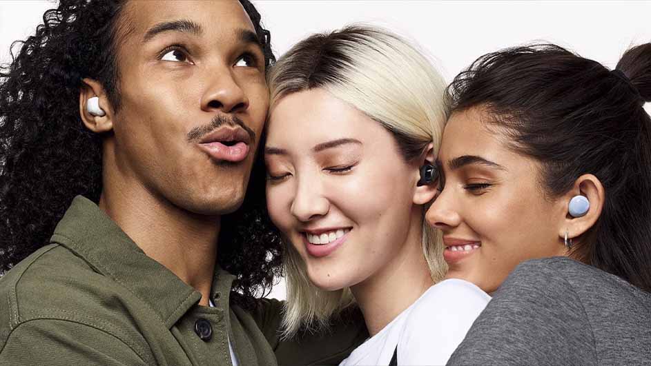 Trois personnes souriantes portent des oreillettes de différentes couleurs : blanc, noir et bleu. Le fond est blanc.
