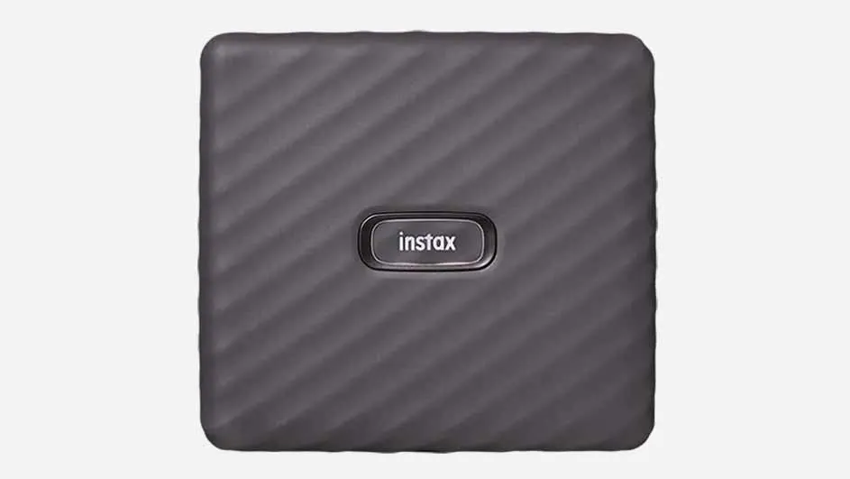 Une imprimante Instax carrée gris foncé à rayures diagonales sur un fond blanc uni.
