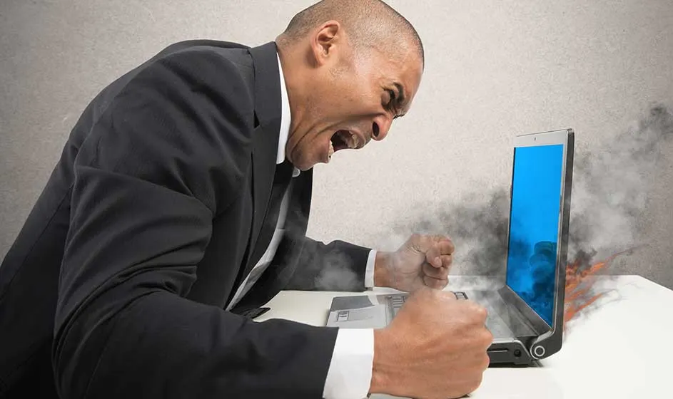 Een woedende zakenman slaat op zijn laptop, terwijl rook uit het blauwe scherm opstijgt en het apparaat lijkt te ontploffen.