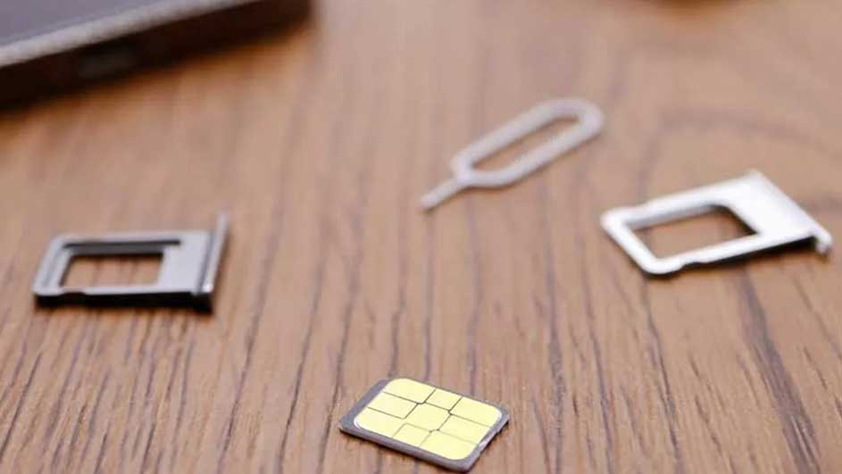 Sur une table en bois, une carte SIM jaune, deux supports SIM blancs et un outil d'éjection SIM blanc sont visibles.
