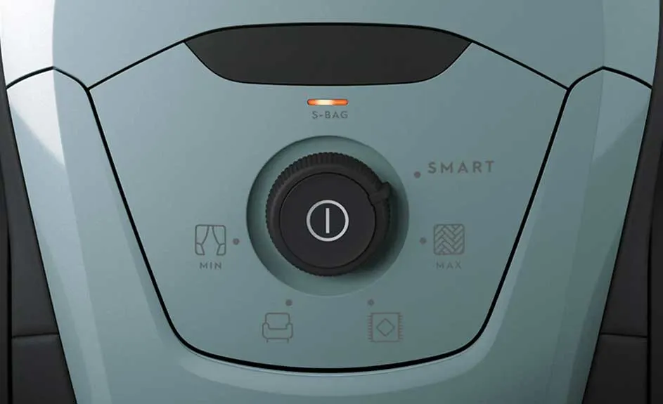 Gros plan d'un aspirateur bleu clair avec un bouton noir central. Des icônes indiquent les réglages min, max et smart. Une lumière orange est visible.