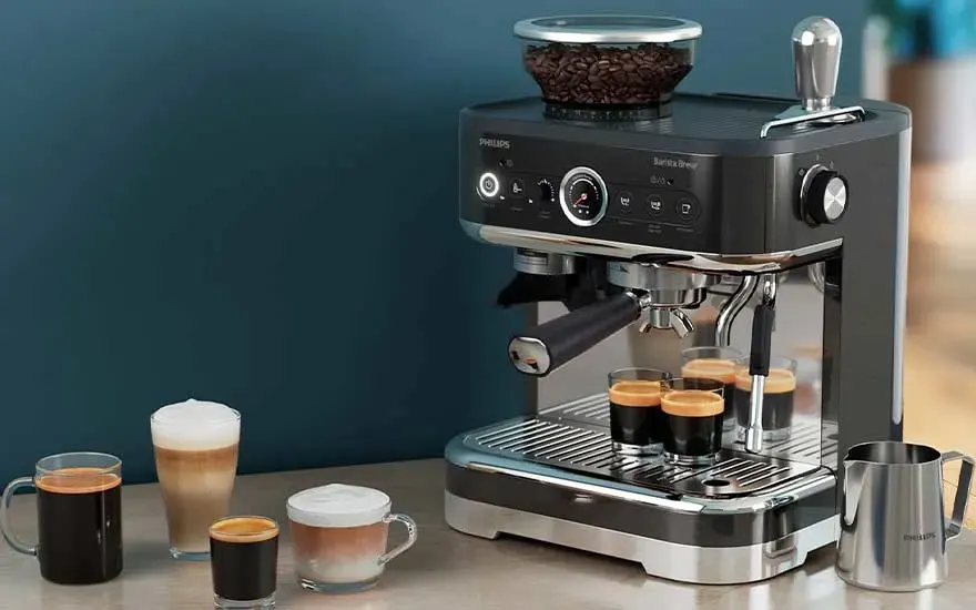 Machine espresso noire avec réservoir de grains au‑dessus, préparant plusieurs tasses entourées de cafés et boissons lactées.