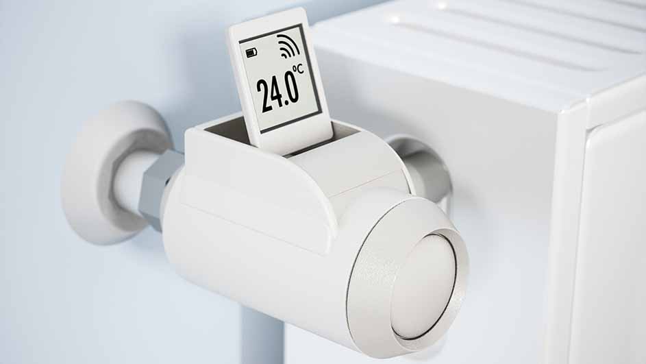 Een witte radiatorthermostaat met een digitaal display dat 24.0 graden Celsius aangeeft, bevestigd aan een witte radiator.
