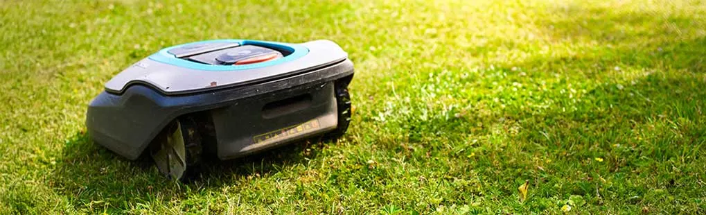Une tondeuse robot Gardena tond automatiquement la pelouse verte sans intervention humaine.