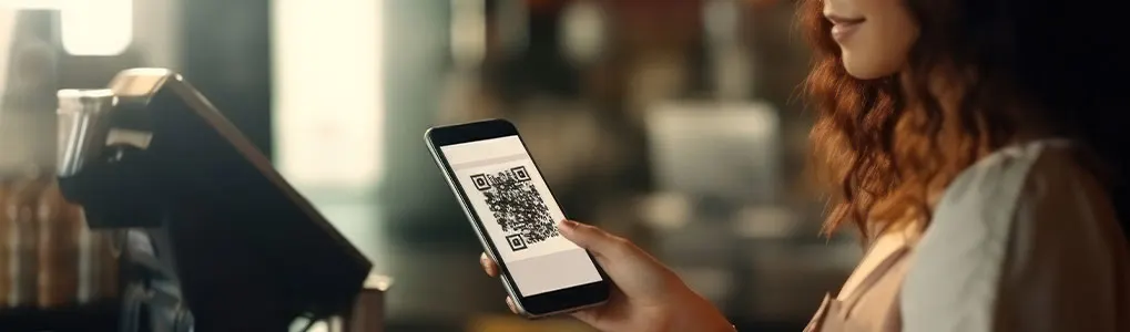 Un terminal noir est à côté d'un smartphone affichant un code QR sur un écran blanc.