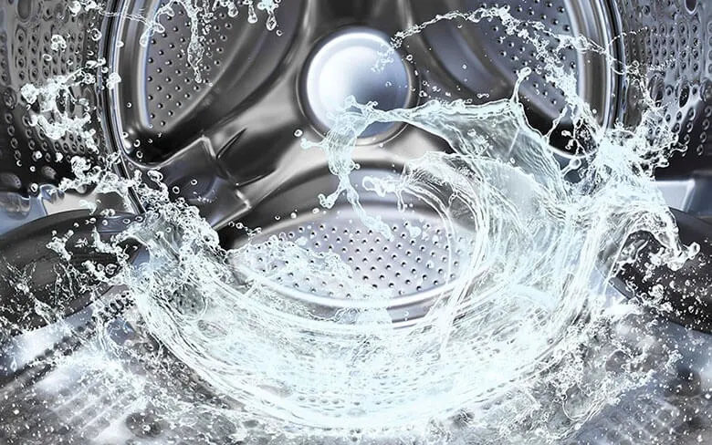 Gros plan de l'intérieur d'un lave-linge en acier inoxydable avec de l'eau en mouvement.