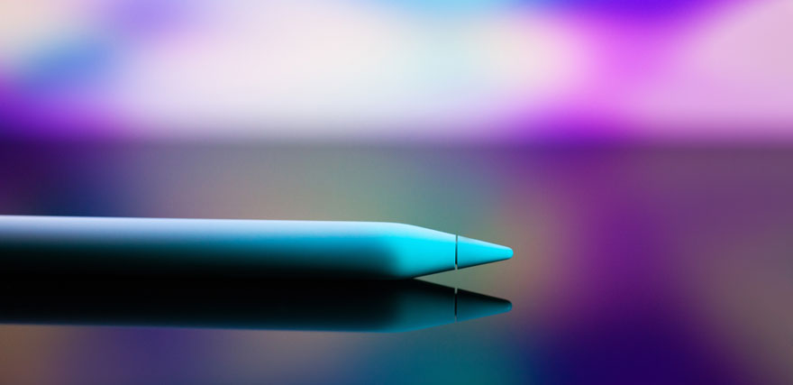 Stylo bleu-vert sur surface brillante avec fond flou violet et blanc. Reflet sombre visible.