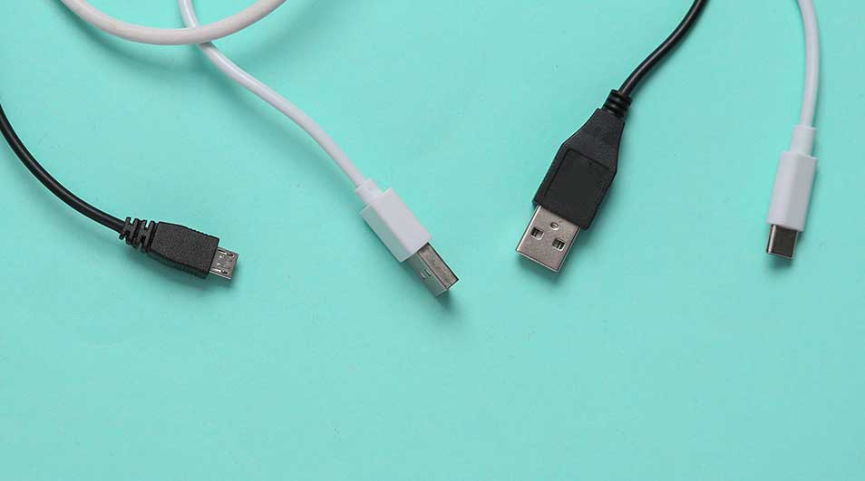 Vier USB-kabels (wit en zwart) liggen op een blauwe achtergrond. De kabels hebben verschillende aansluitingen.