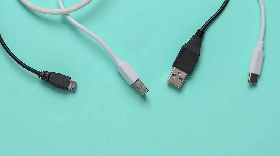 Quatre câbles de données (USB-A, USB-C et micro-USB) noirs et blancs sur fond turquoise.