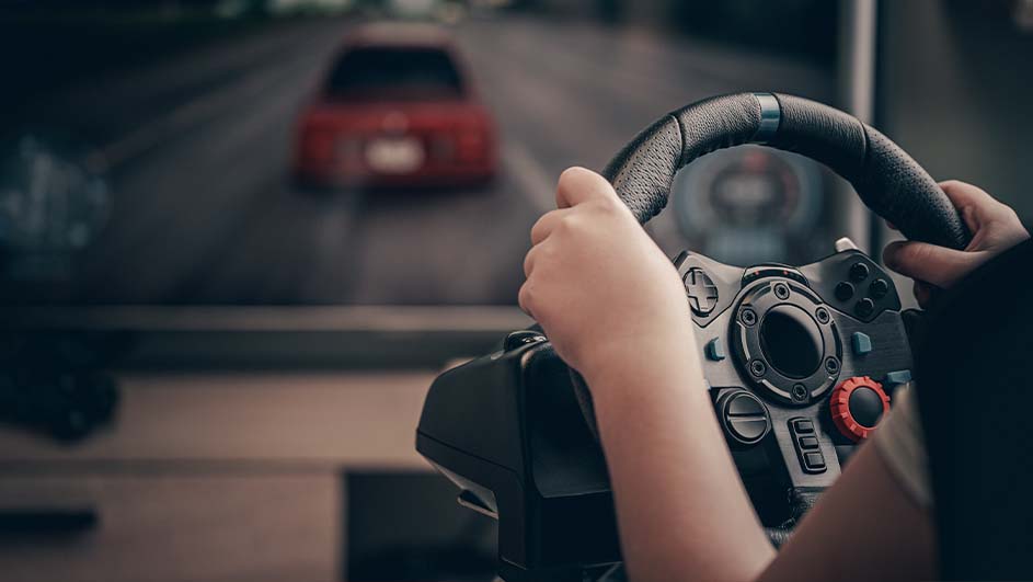 Une personne utilise un volant de jeu avec une voiture rouge sur un écran en arrière-plan.
