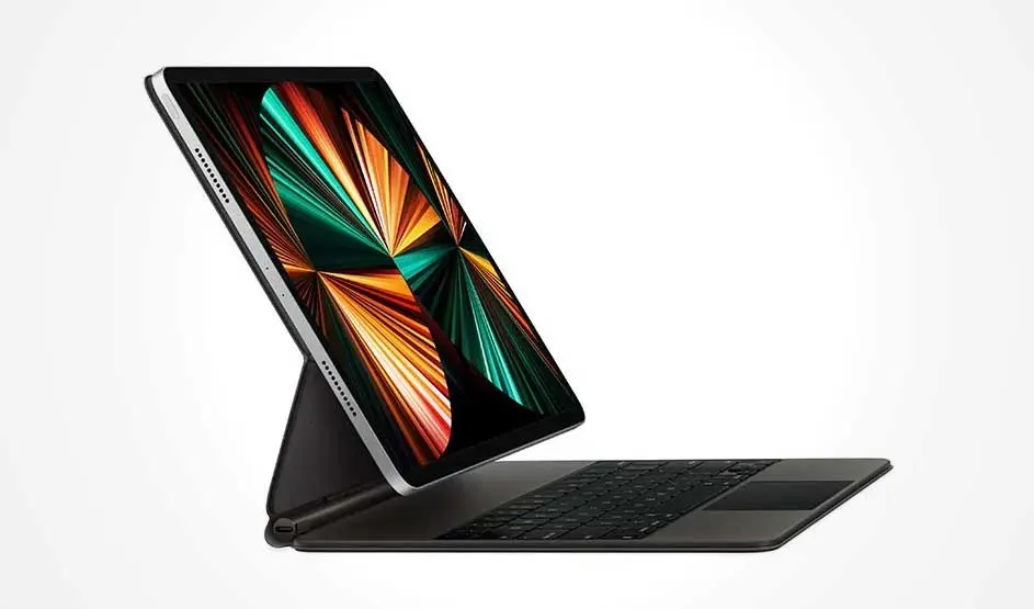 Tablette avec clavier noir. L'écran affiche des motifs géométriques verts, orange et noirs. Fond blanc.