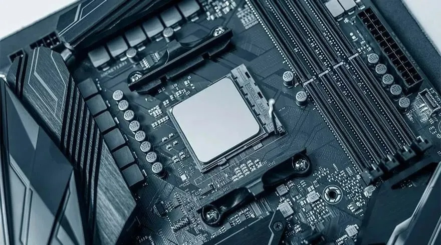 Close-up of a dark gray computer motherboard with a central processor unit (CPU) and expansion slots visible.