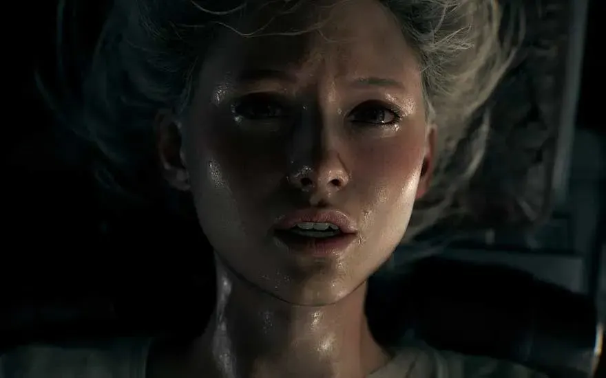 Dit is een videospel. Close-up van een bezwete vrouw die ligt, ogen wijd open en angstig; hard licht snijdt door de schaduw rond haar gezicht.