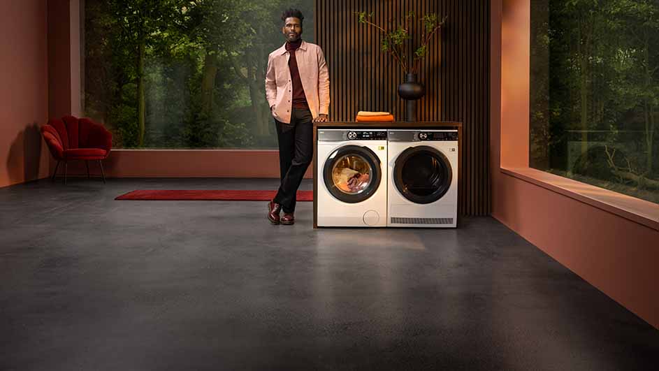 Deux machines à laver blanches sont placées devant un mur en bois dans une pièce avec une fenêtre donnant sur des arbres.