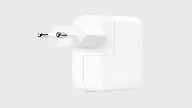 Een witte telefoonoplader met twee metalen pinnen steekt uit een wit stopcontactblok.