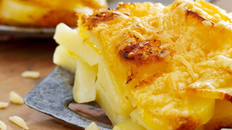 Gratin dauphinois sur une spatule grise, avec du fromage fondu doré sur le dessus.