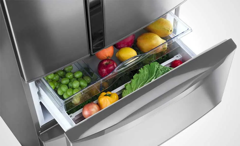 Réfrigérateur en acier inoxydable avec tiroir ouvert plein de fruits et de légumes.