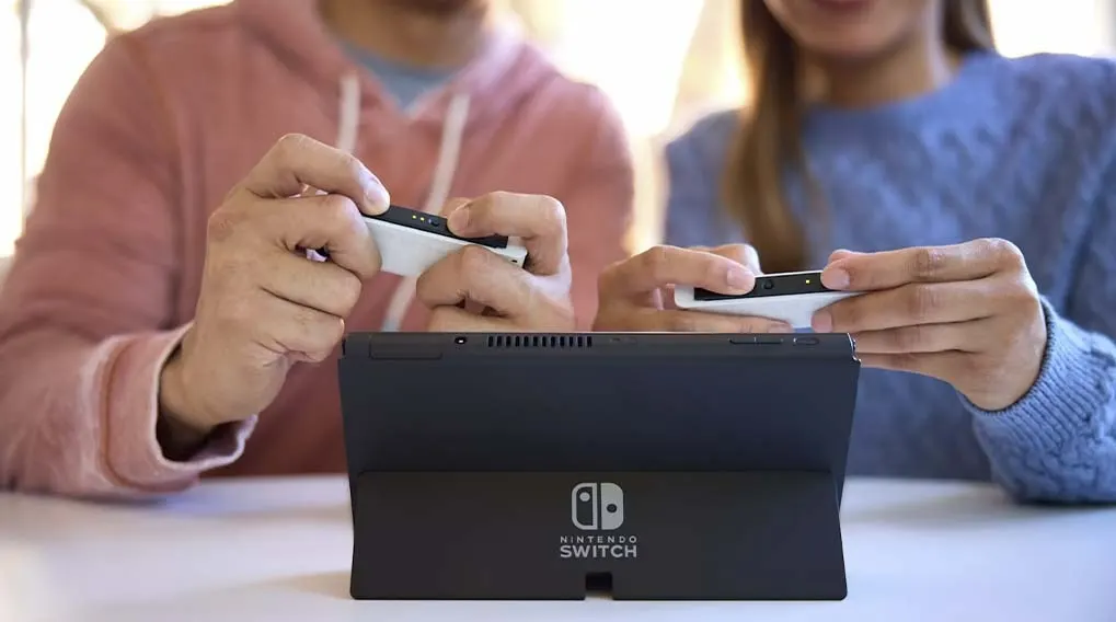 Een zwarte Nintendo Switch staat op een witte tafel, met twee witte Joy-Cons die eraan worden bevestigd.