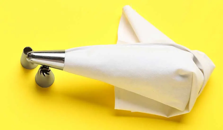 Un sac à douille blanc avec des embouts en métal sur un fond jaune vif.