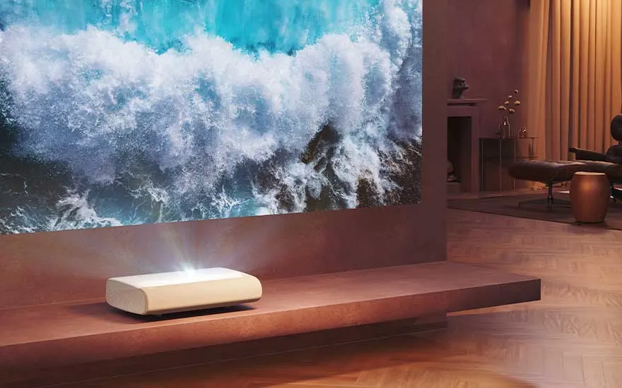 Dans un salon moderne, un projecteur compact affiche de magnifiques vagues sur un grand écran mural pour une ambiance cinéma.