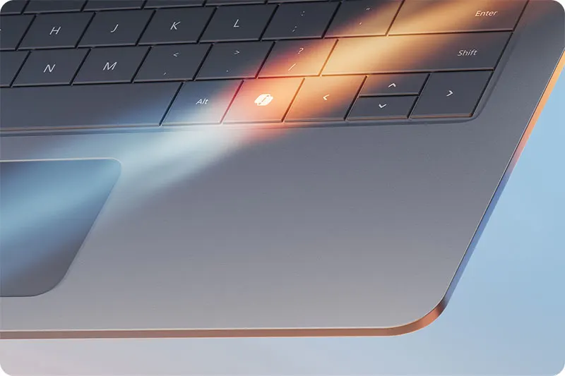 Vue rapprochée d'un clavier gris foncé avec des touches carrées, un trackpad et un éclairage ambiant chaud.