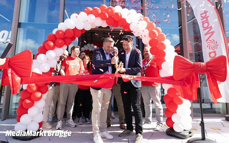 Feestelijke opening van MediaMarkt Brugge, met rood-witte ballonnen, lint, grote schaar en glimlachend team.