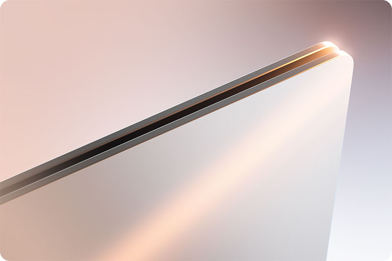 Gros plan d'un ordinateur portable blanc aux bords métalliques fins, avec un éclairage doux créant des reflets sur la surface.