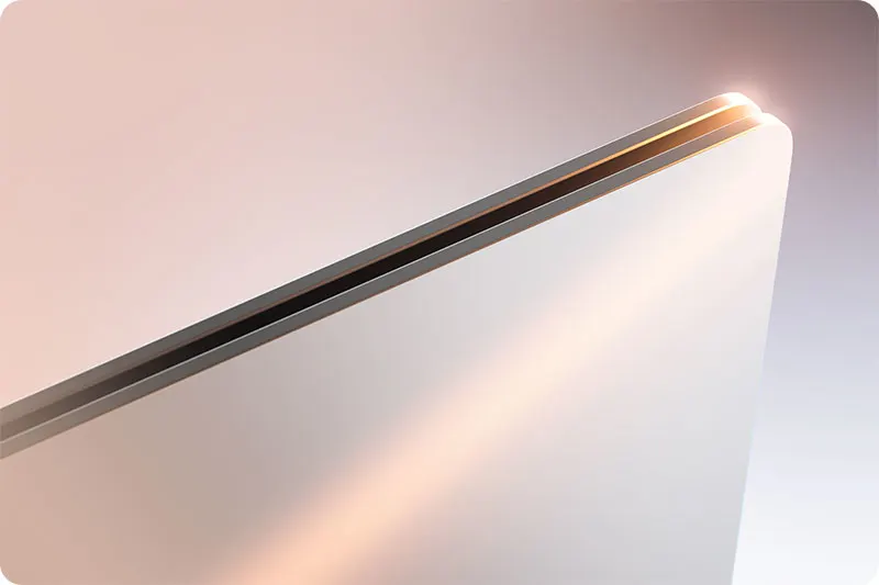 Gros plan d'un ordinateur portable blanc aux bords métalliques fins, avec un éclairage doux créant des reflets sur la surface.