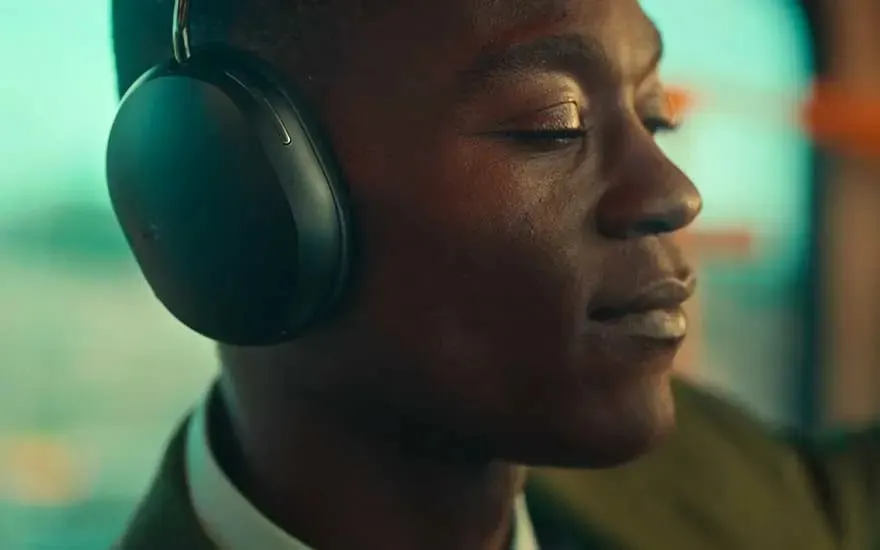 Un casque noir sur une tête, profil droit, sur fond turquoise et orange.