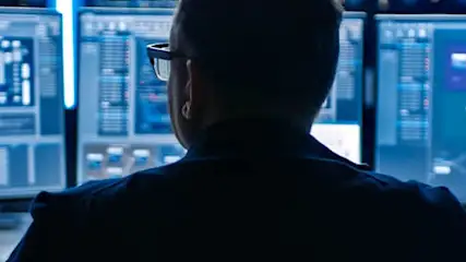 Un écran d'ordinateur bleu affiche des données réseau. Des graphiques et du code sont visibles. Plusieurs écrans affichent des informations différentes.