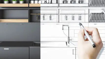 Een keukenontwerp, half foto, half schets, toont kasten, een aanrecht en een hand met een pen op de schetskant.