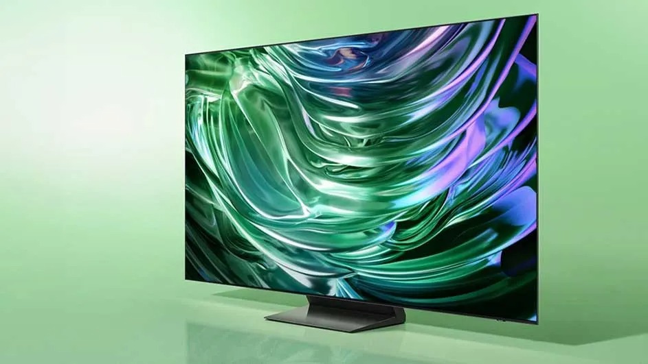 Une télévision Samsung moderne est posée sur un fond vert et affiche une image abstraite aux effets brillants verts et violets à l’écran.