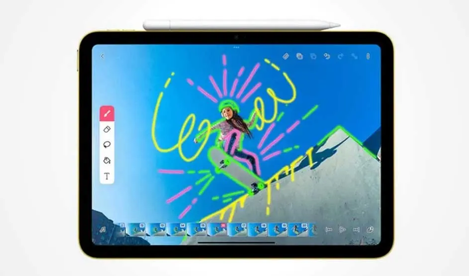 Tablette dorée affichant une image avec des dessins colorés sur un fond de ciel bleu et de montagne enneigée. Un stylet repose sur le dessus.