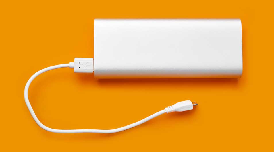 Een witte powerbank is met een witte kabel verbonden op een oranje achtergrond.